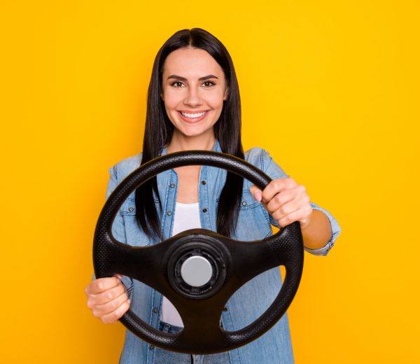 Portrait of her she nice-looking attractive lovely pretty charming cheerful brunet girl turning steering wheel isolated on bright vivid shine vibrant yellow color background
